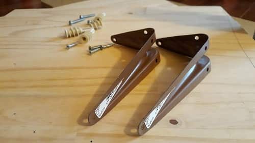 Screws, wood, and shelf brackets laid out for DIY cat shelves.